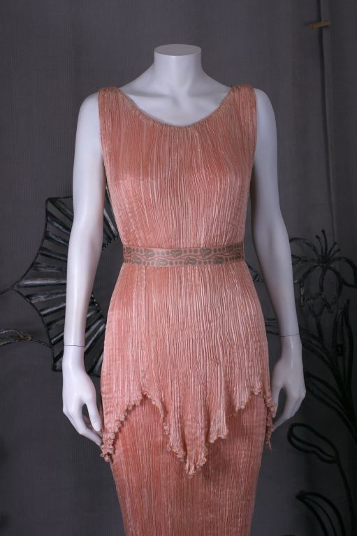 This dress is made of finely pleated  shell pink colored silk with silk cording along side seams ,shoulders , and tunic hem, and  mat frosted colored glass beads threaded through the cording.
The Peplos worn by the women in ancient greece was an