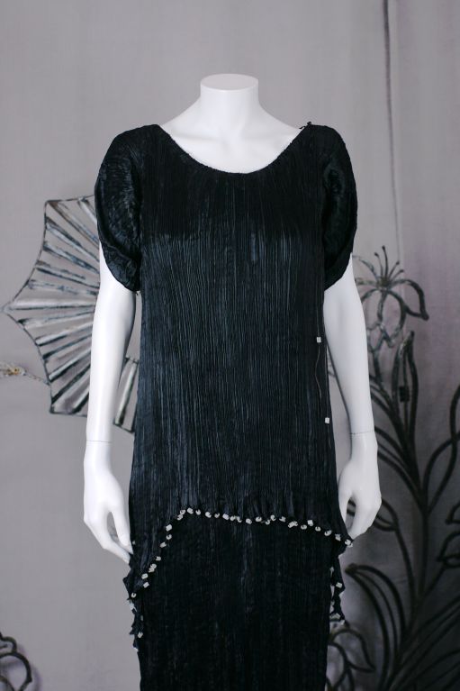 This dress is made of finely pleated black colored silk with silk cording along side seams,shoulders and tunic hem with  matte frosted colored glass beads threaded through the cording.<br />
The Peplos worn by the women in ancient greece was an