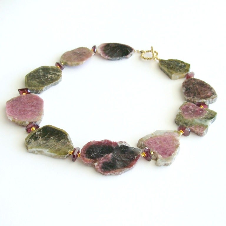 Organic tourmaline slices - with their gorgeous earthy mix of greens, pink merlot and black are gently separated with transparent pink rhodolite garnet nuggets - to create this dramatic necklace.  The stones are polished and smooth - but the natural
