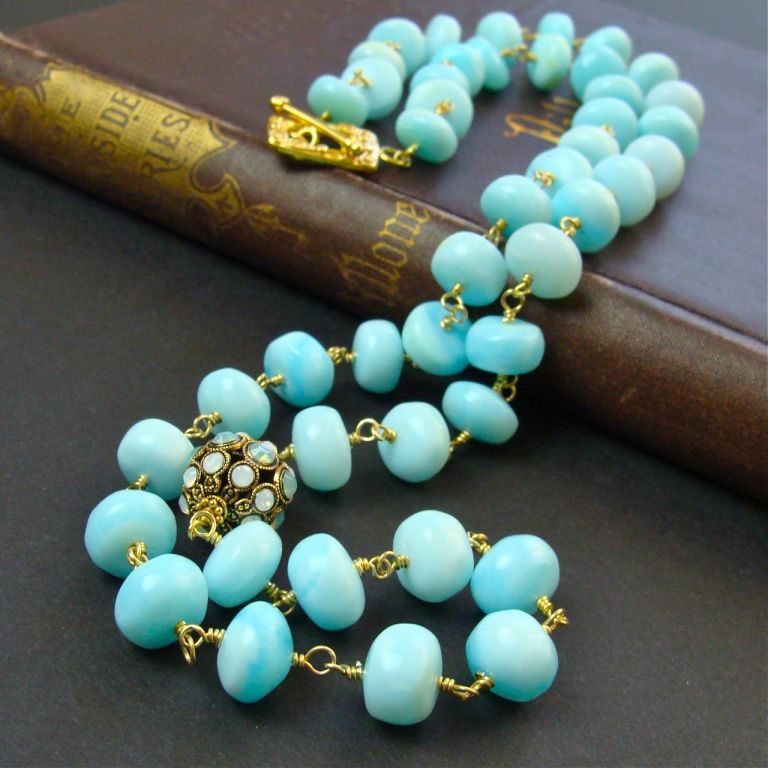 A simply elegant design of rosary linked smooth Peruvian Blue Opal rondelles with an asymmetrical antiqued filigree focal bead allows the true beauty of these stones to shine.<br />
<br />
28” long.
