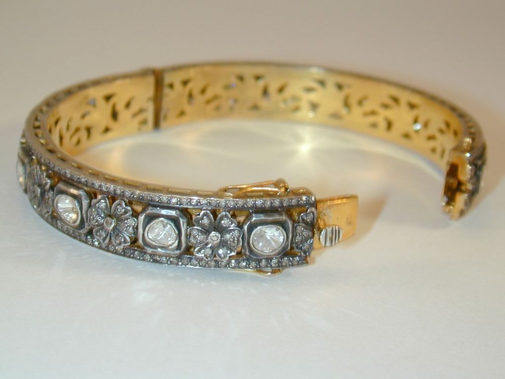 Pair of Indian silver-topped yellow gold hinged bangle bracelets with a floral motif set with rose cut diamonds.