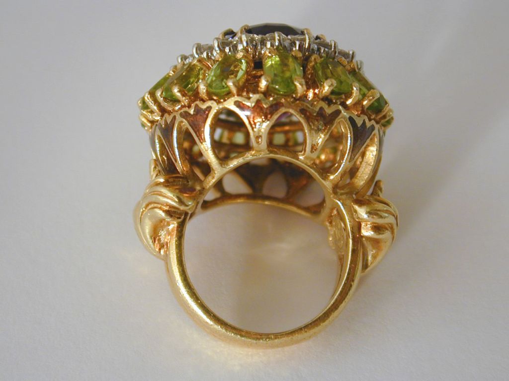 Large 18KT yellow gold ring with center oval faceted amethyst weighing approx. 11.65cts surrounded by 22 round diamonds weighing 2.20ctTW above 15 oval faceted peridot with enamelling under the set stones around the bridge. Stamped La Triomphe. Size
