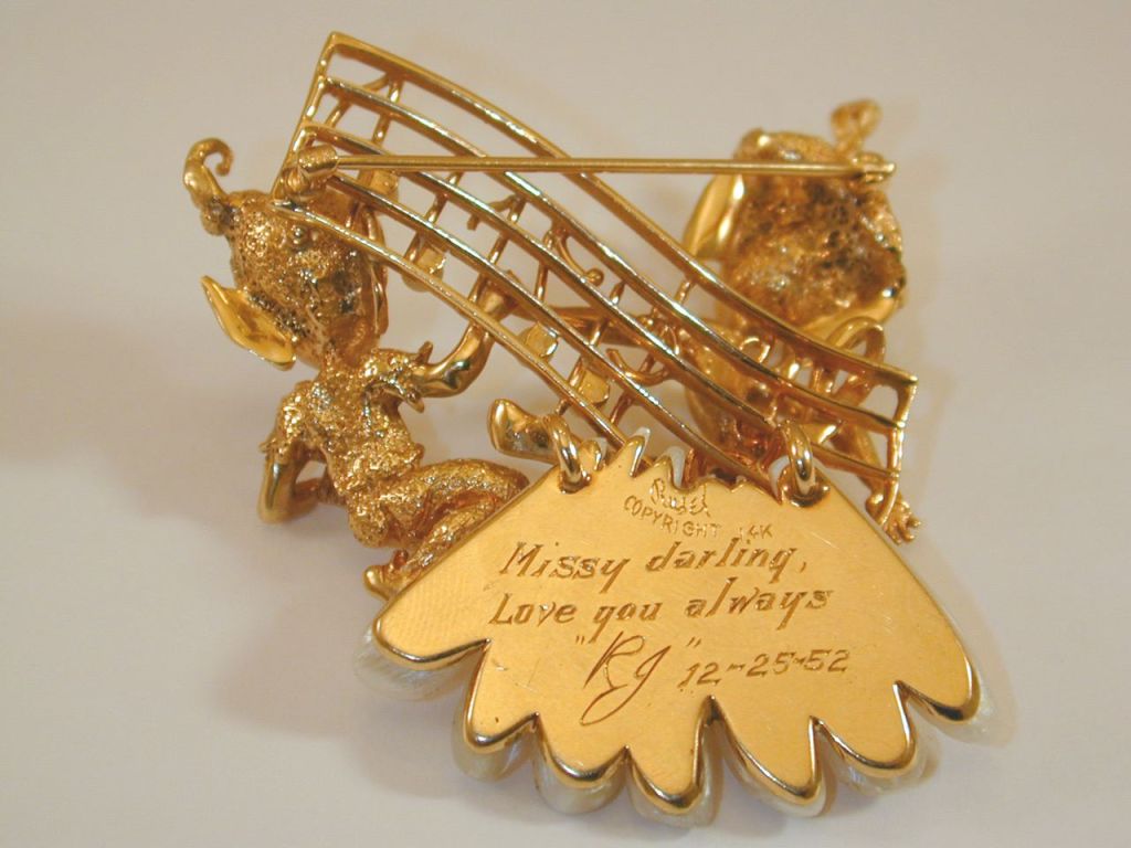 14KT yellow gold brooch depicting two Christmas elves holding a treble clef staff w/ pearl “notes” & sitting on a cloud of freshwater pearls. <br />
Inscribed from Robert “RJ” Wagner to Barbara “Missy” Stanwyck. “Missy darling  Love you always ‘R