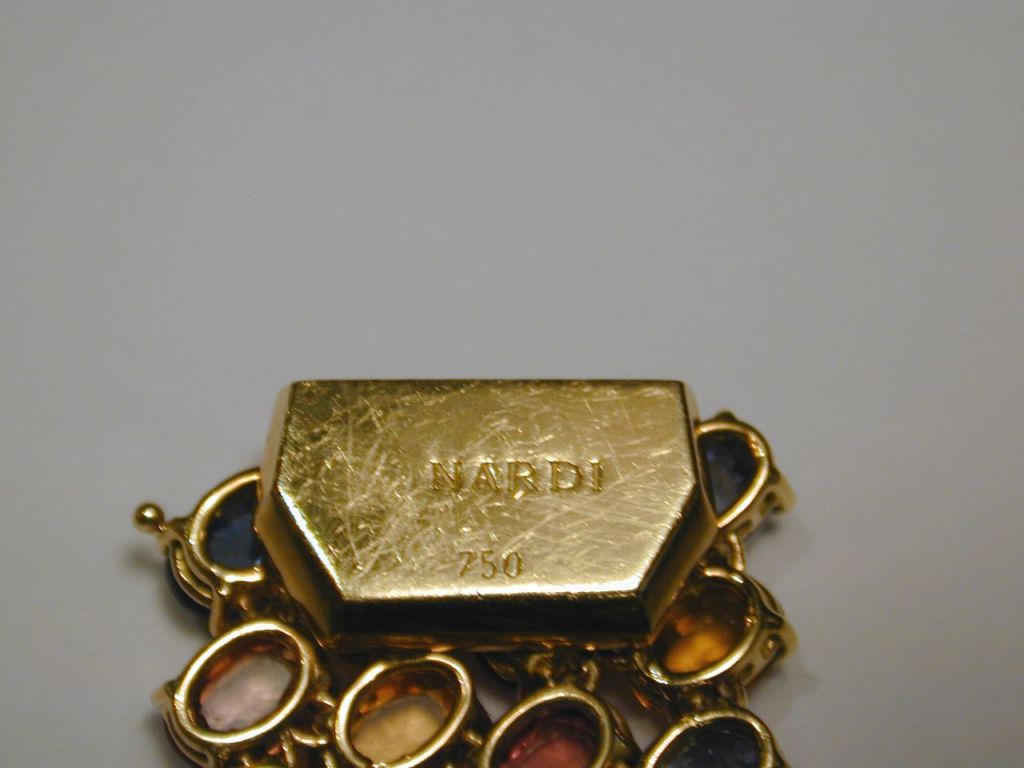 18KT yellow gold flexible, articulated bracelet of oval faceted multi-colored sapphires all four-prong set with the pavilion up. Signed Nardi.