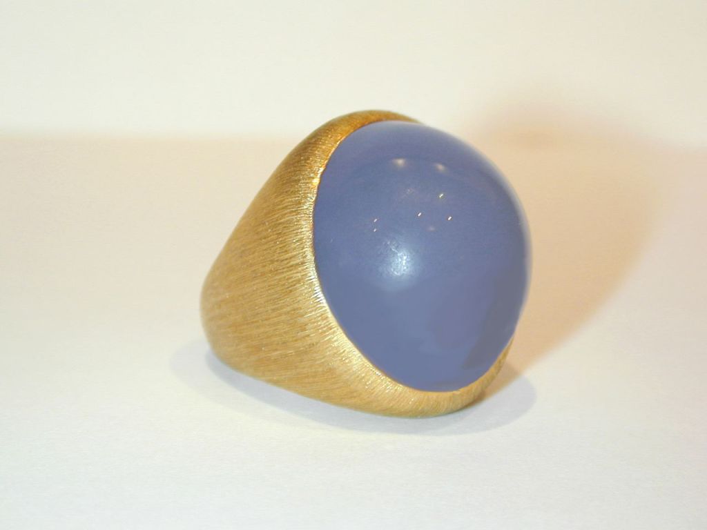 Heavy textured yellow gold ring with a bezel-set round cabochon blue chalcedony at center. Signed Henry Dunay.