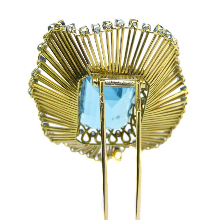 Sterle brooch featuring a central aquamarine weighing approximately 40ct.  The brooch is framed in undulating gold wirework and surrounded by a frame of sapphires and diamonds.  Signed STERLE PARIS, French Hallmarks.