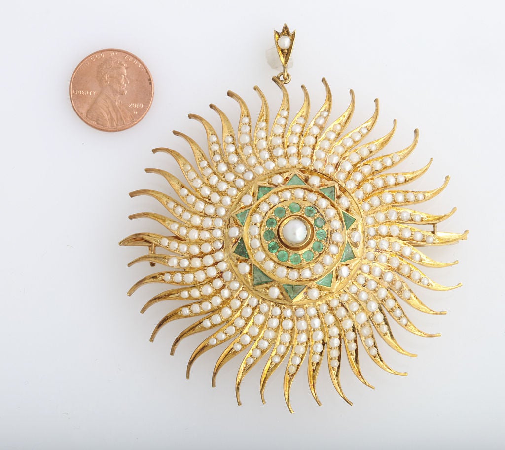Emerald and natural pearl brooch featuring massive stylized sun burst design. Centrally set with 22 emeralds weighing approx. 1.50 cts total framed with 251 fresh water pearls measuring 1.80mm-5.30 mm wide in a hand made 14k yellow gold mounting