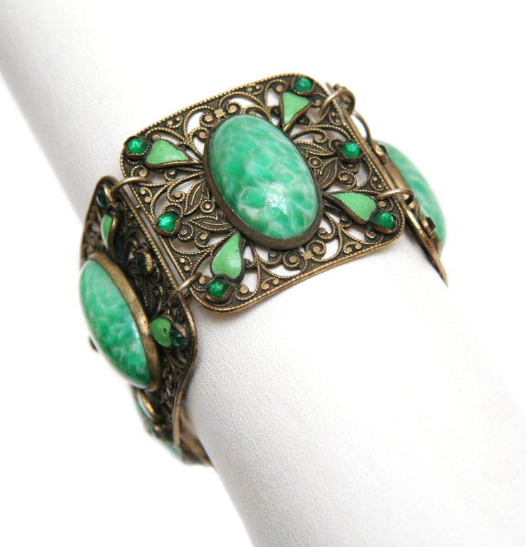 Antiqued gold toned filigree link bracelet with large oval jadeite cabochons, green rhinestones, and enamelled accents.