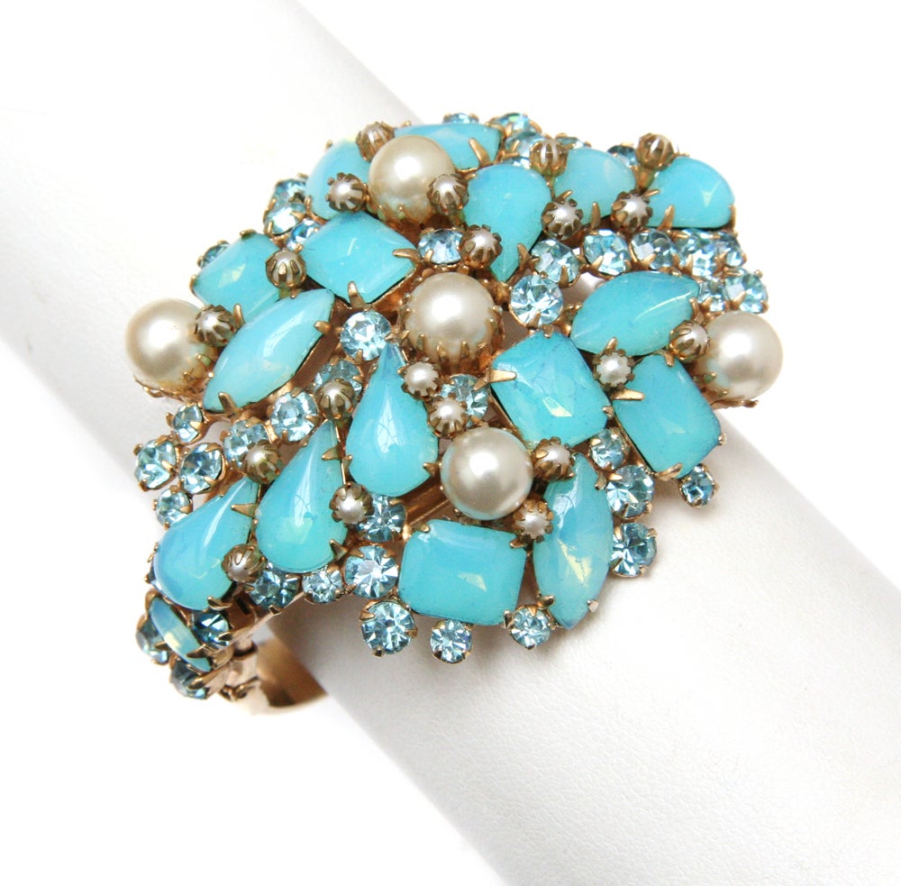 Signed Alice Caviness hinged cuff featuring aqua stones and pearl accents, set on gold toned metal.