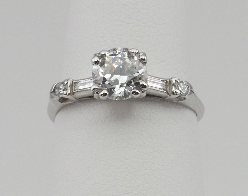 This ring is a lovely example of simple elegance. The center diamond is a 1.07 carat Old European Cut diamond that is F in color SI1 in clarity (per GIA certificate). It is set with a baguette and round diamond on each side. Circa 1930s.

GIA