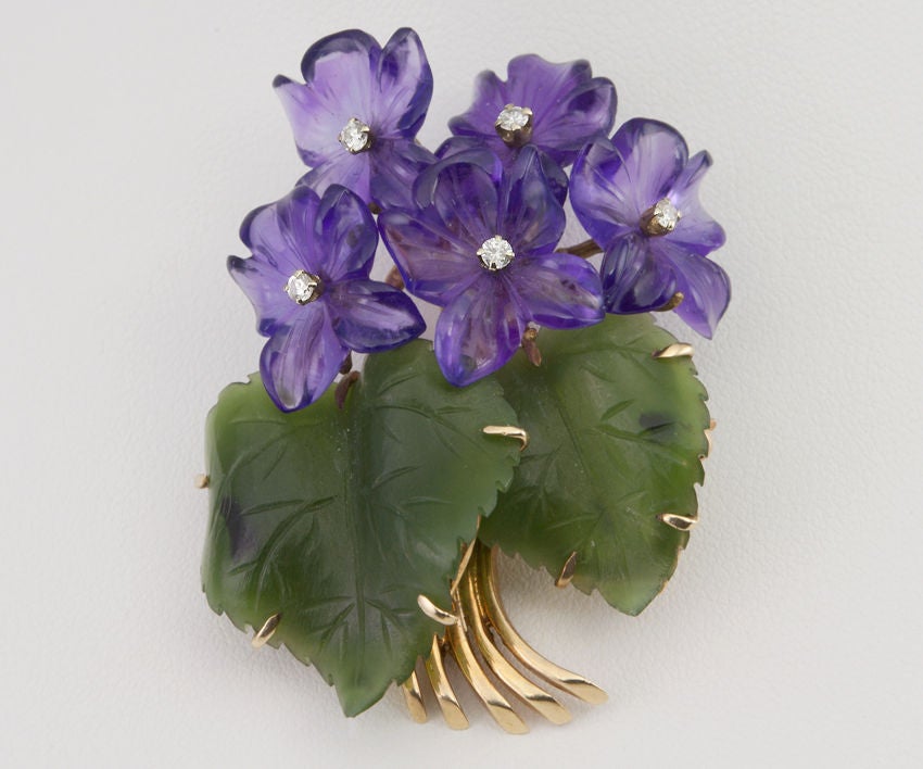 This sweet pin is a bouquet of Amethysts cut into violets,with diamond centers. The bouquet is completed with jadeite leaves and gold stems peeking out the bottom.