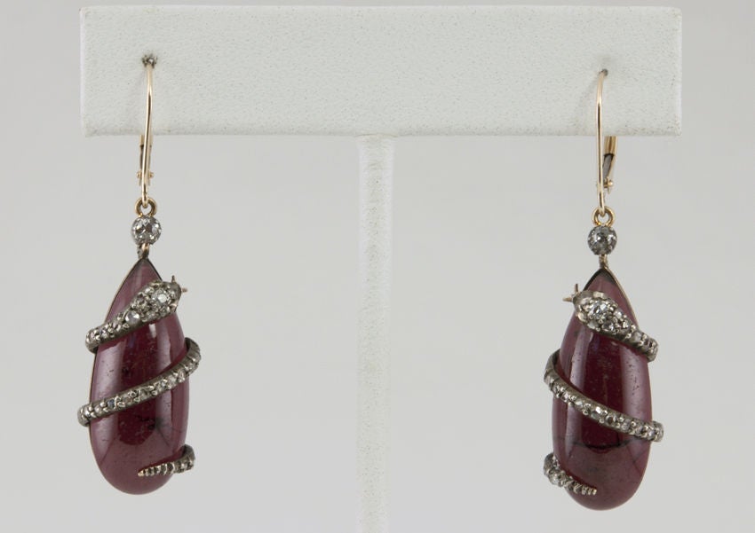 I LOVE snake anything!  These are such a great example of victorian very moody diamond snake earrings. The snakes are silver with rose cut diamonds and an old european cut in the head.  They wrap around a teardrop shape cabochon cut garnet.<br