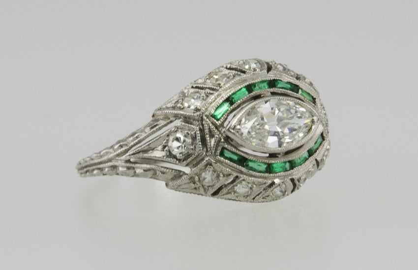 This beautiful ring has a center marquise diamond .50ct I-VS2 set sideways,which is unusual.  Surrounding it is a channel of baguette cut emeralds, and numerous single cut diamonds in gorgeous cut out work.  Also, this ring is engraved within an