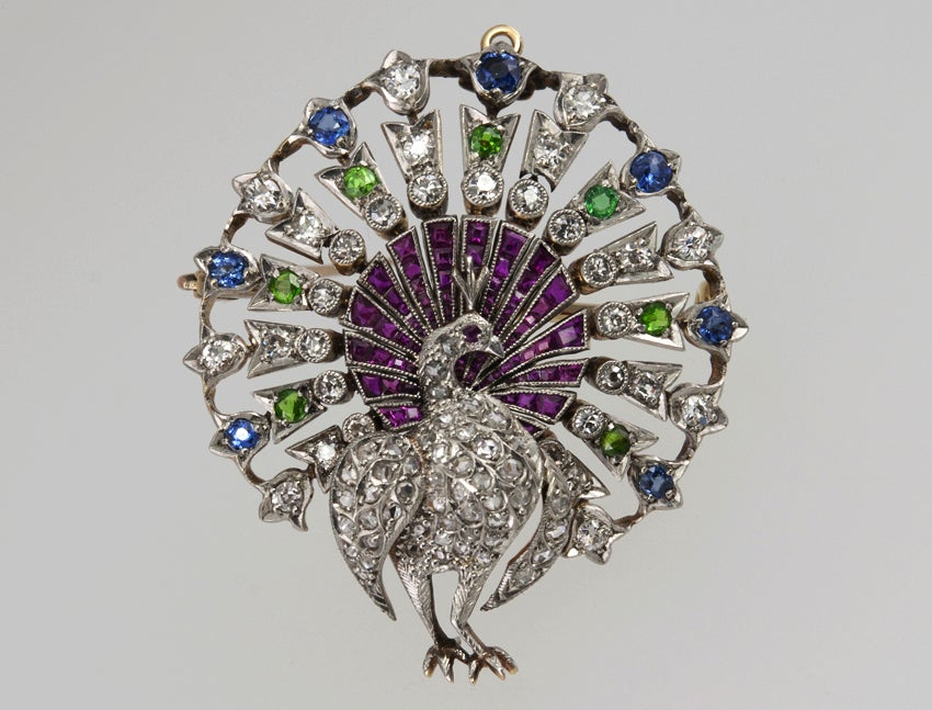 A peacock in full regalia! He is splendid ! and his body is filled with rose cut diamond.  His tail feathers are all sapphires, rubies and demantoid garnet, in addition to old european cut diamonds.  Really,really special!