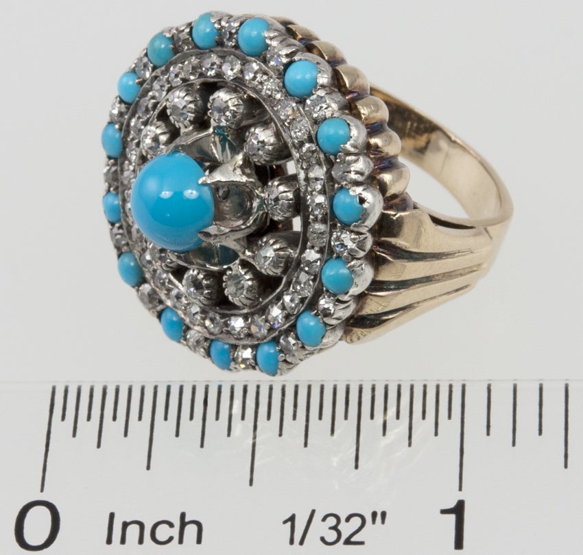 Diamond and turquoise cluster ring with a 14 karat yellow gold ring shank and a round sterling silver top with circles of Old European Cut diamonds; approximately 1 carat of total diamond weight, and beautiful persian blue turquoise cabochons. Circa