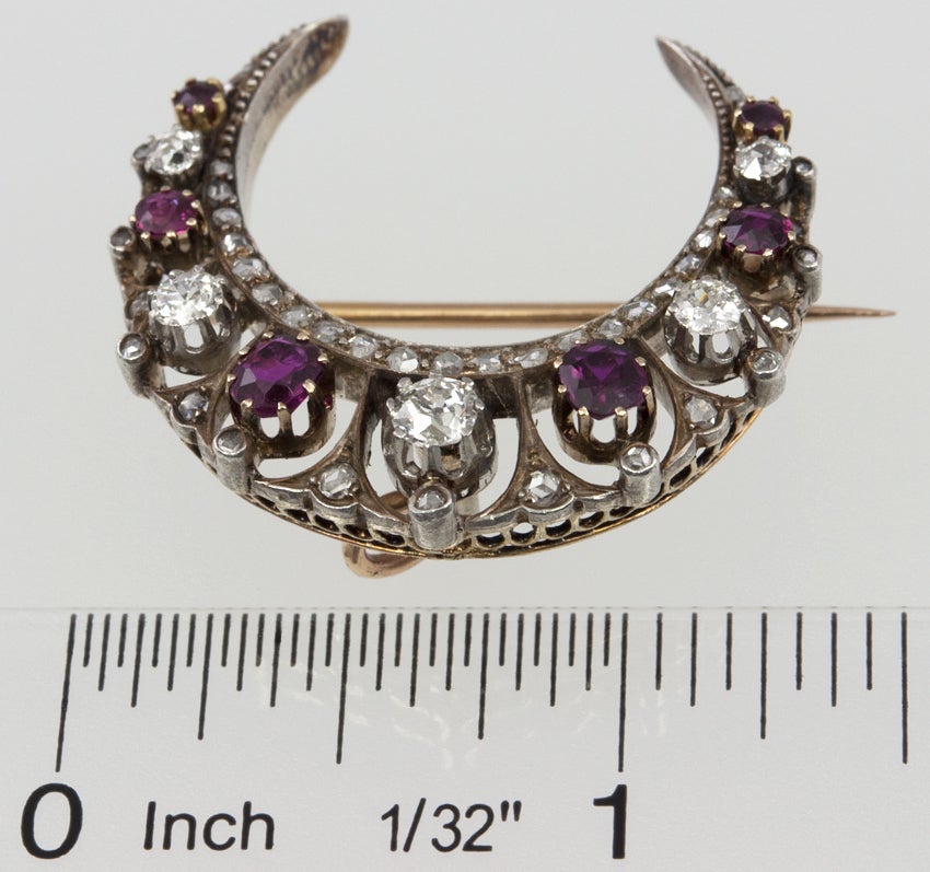 This is a gorgeous example of a Victorian crescent brooch!  Silver top and 18k gold back with six old moody rubies and lots of old european cut and rose cut diamonds.  There is a fold down bale for a chain to wear as a pendant. The pinback is also