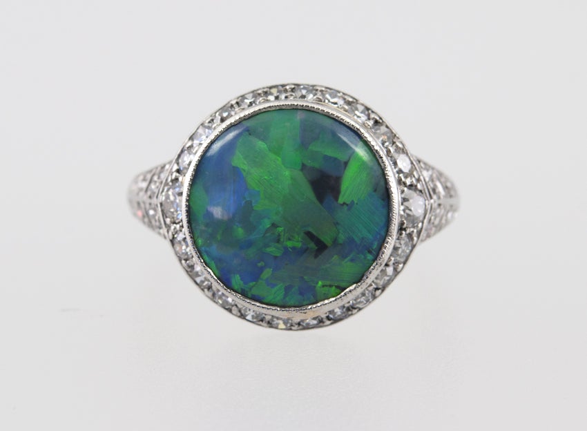 Stunning platinum ring with center bezel set black opal, surrounded by old full and single cut diamonds., that also taper down each side. Really unusual and beautiful! Signed JE Caldwell.

Currently a US size 5.34 and easily adjustable.