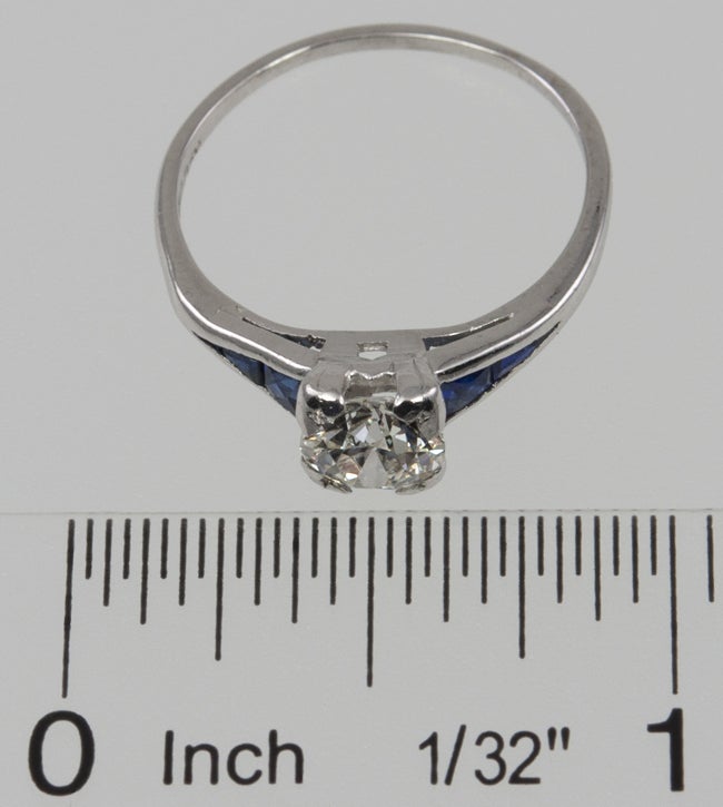 Art Deco vintage platinum ring from circa 1930s.  This beautiful ring features a 0.91 carat Old European Cut diamond that is G in color and VS1 in clarity (per EGL certificate). On each side of the diamond are two old cut calibre sapphires.  This