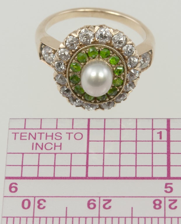 14k yellow gold ring with an outer circle of old european cut diamonds 1ct total weight.  Next is a circle of those rare demantoid garnets, and then a center pearl. There is one diamond on each side of the shank as a finishing accent.