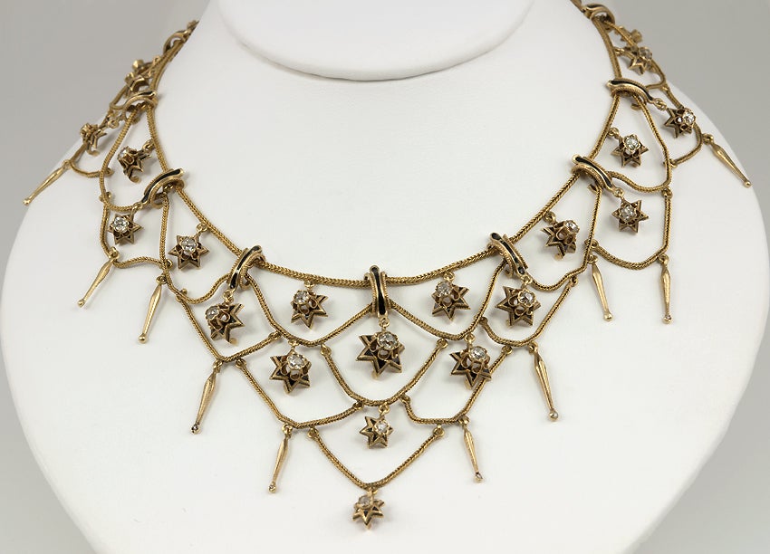This is such an unusual necklace!  French, 18k yellow gold, it is composed of gold chain, swaged in a very Victorian style, with the open spaces filled with diamonds.  These old european cut diamonds are inside gold and black enamel stars.  There is