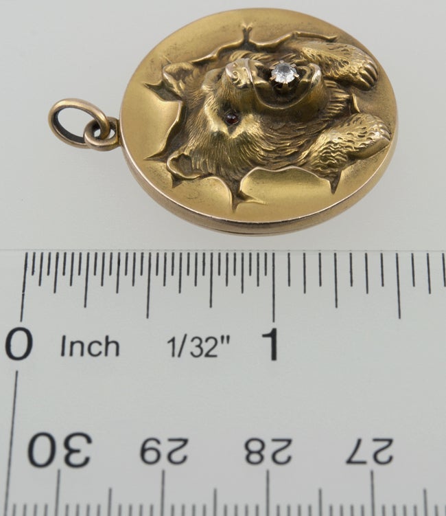 Such Drama!  This is a 10k Yellow gold round locket with a bear bursting out! He has garnet eyes and an old european cut diamond in his mouth. ROAR!