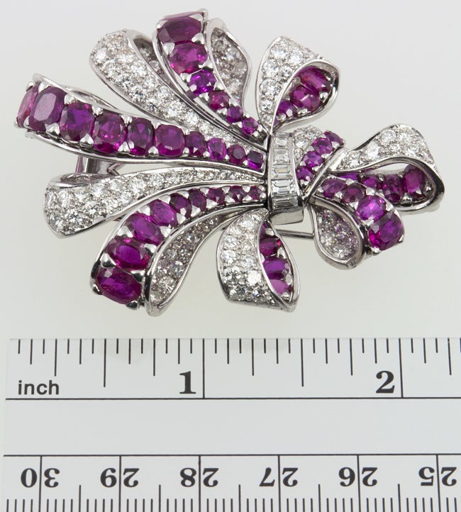 A large platinum ribbon brooch with approximately 8 carats of full cut round diamonds, transitional cut round diamonds and diamond baguettes,  all G-H color SI clarity.  There are also approximately 10 carats of natural round and oval cut rubies.