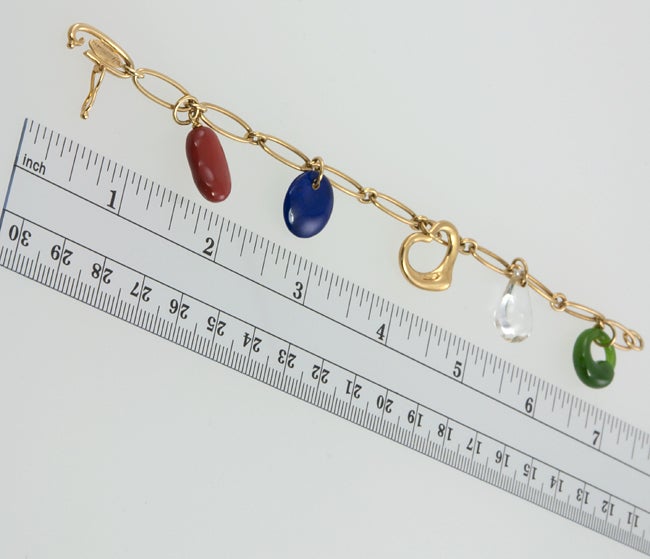 18k charm bracelet signed by Elsa Peretti, TIFFANY & CO with her trademark floating heart charm, coral bean,lapis disc,jade open circle and a rock crystal teardrop.
