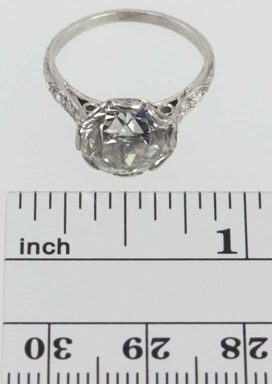 Platinum incredible turn of the century mounting, holding an old european cut round diamond 3.95 carats, K-SI2 with a GIA certificate.  There are three additional small old cut diamonds down each side, with tons of engraving.  Stunning!