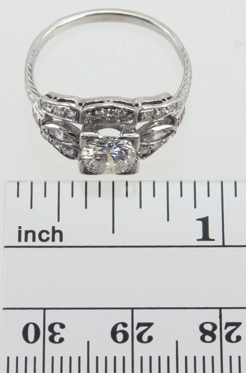Art Deco diamond and platinum engagement ring set with single cut diamonds, and two marquise cut diamonds, which all complement a center transitional round brilliant center diamond.  The diamond is box set and approximately 0.90ct I-SI2. This ring