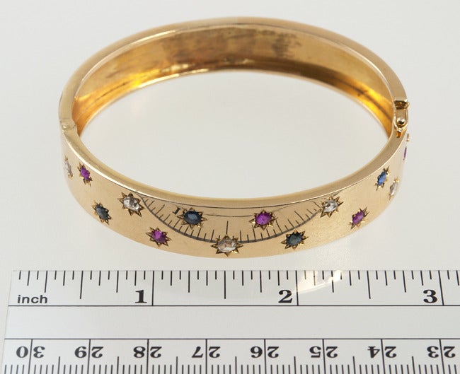 18k yellow Victorian gold bangle, that is 1/2' wide and has five rubies, four blue sapphires and four rose cut diamonds all in star style settings.
