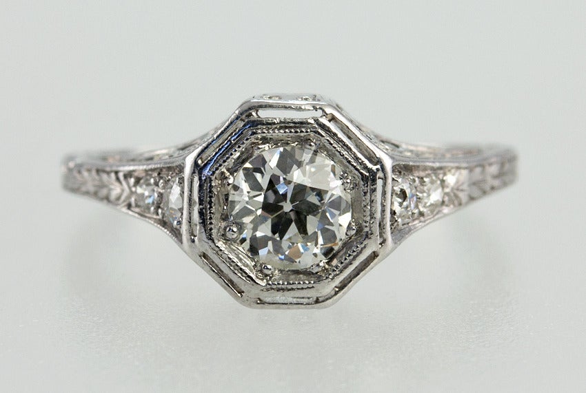 Platinum engraved ring with .75 carat center old european cut diamond set into an octagonal bezel.  The color is approximately H-I and the clarity is SI2. There is a full cut and single cut diamond on each side.  This is a lovely period engagement