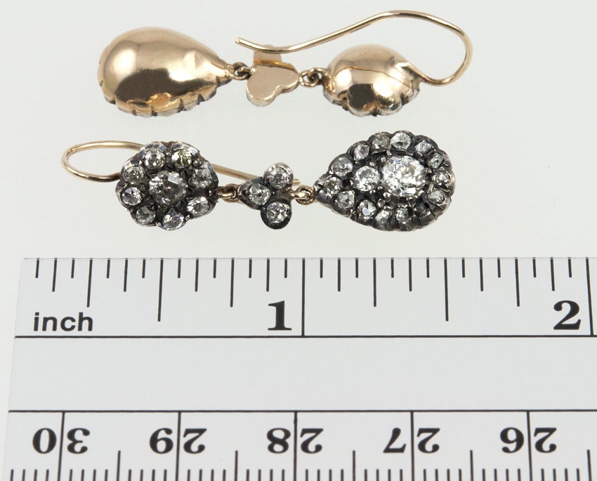 Victorian silver topped 14 karat yellow gold earrings, set with over 2 total carats, 28 diamonds total, of Old Mine Cut diamonds and rose cut diamonds, with a flourette top leading to a pear shape drop.  The gold hooks make them easy to wear.