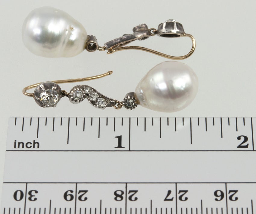 These Victorian dangle earrings are from around 1880, with old cut diamonds set in silver topped 14K yellow gold, which was correct for that period.  There is approximately one carat of diamonds total, leading to a baroque pearl drop, each pearl is