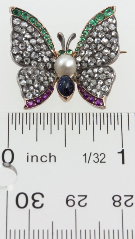 Silver top with gold back butterfly pin.  This beautiful  Victorian specimen is covered in rose cut diamonds, with a trim of emeralds and rubies.  The body is composed of a cabochon sapphire and a pearl. She's gorgeous!