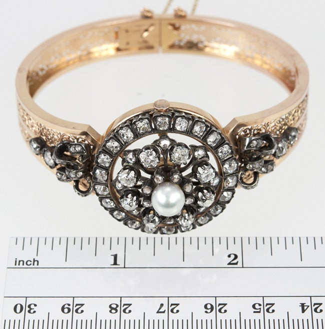 This 18k French yellow gold Victorian cuff has a stunning combination of 4 carats of rose and cushion cut diamonds, with a center pearl.  The circular piece in the center is removable to wear as  a pendant. The filigree is ridiculous on this