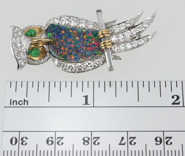 Platinum and gold owl sitting on a branch brooch.  His body is made of a beautiful black opal, the face and feet are gold with cabochon emerald eyes.  Then the whole thing is paved with 2 carats of  great quality diamonds. Circa 1960s.

Width: 0.70,