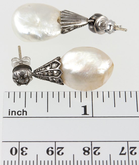 These earrings are from the mid 1800's. They are silver with approximately .50cts of rose cut diamonds on the cap, leading to big juicy baroque pearls.
Although they are slightly different colors, they are not as drastically different as the photos