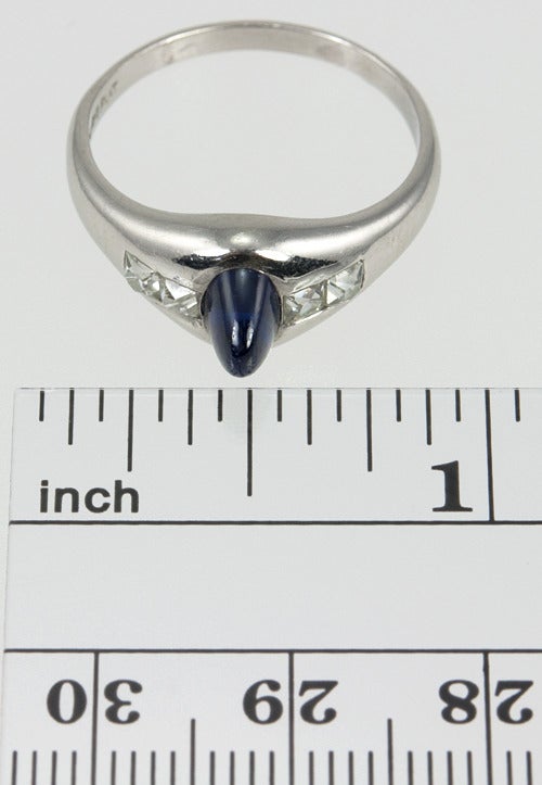 A dramatic cabochon sapphire sits center of 4 French cut diamonds in this amazing Art Deco ring. 0.50 carat blue sapphire and 0.80 carats of French cut H-I VS-SI diamonds.