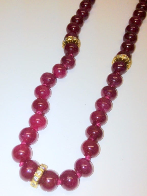 3 gold and diamond rondels accent these 88 round natural ruby beads which are medium to dark red in color.  The matching rubies are 2 mm up to 7.2 mm in diameter.  The strand is completed by an 18K gold clasp and is 21 inches in length