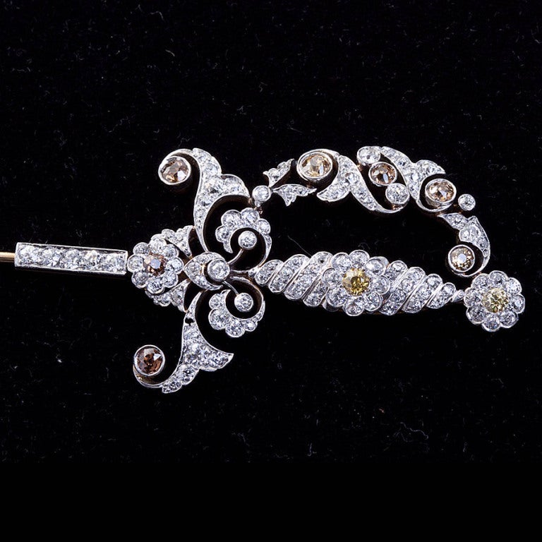 A diamond encrusted early 20th century jabot sword pin with a handcrafted stylized hilt containing white and champagne color diamonds. Scabbard is also diamond inlaid.

No. 4345