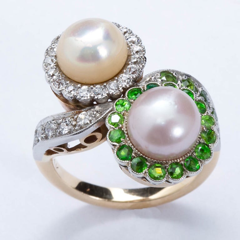 Twin natural pearls set in yellow gold with diamond and demantoid halo borders. Pearls are 7mm size and a creamy white withslight pink overtones. Ring sized to fit 3 to 8 US.

No. 2864 