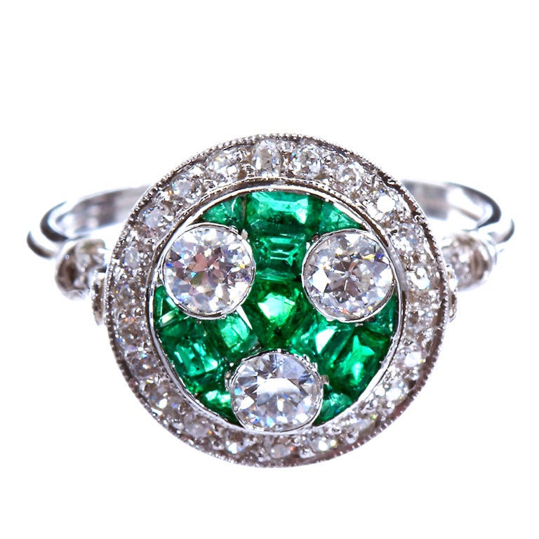 Three Old European cut diamonds weighing ~0.70 cts total set in a bed of calibrated cut emerald with a round diamond border of ~0.30 cts in platinum fancy setting.

No. 2491