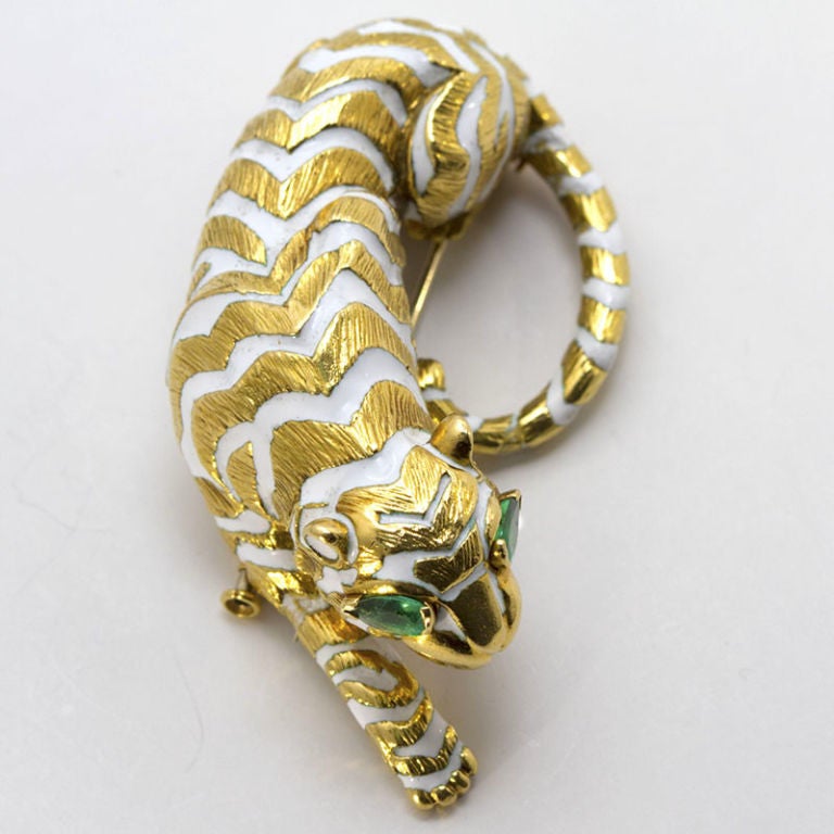 David Webb crouching tiger brooch of 18k yellow gold and white enamel with striking pear shaped emerald eyes.
Weighs 54.5 gram, emerald eyes are 6 x 4 mm.