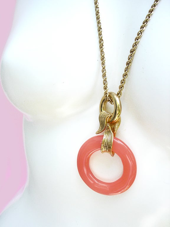 Fabulous Givenchy necklace . . . Oversized, peachy/coral-colored resin loop attaches with a twisting golden ribbon and golden circle to a long, liquid chain. The pendant looks like peach hard-candy, smooth and tactile. Nice weighty heft. Shimmering