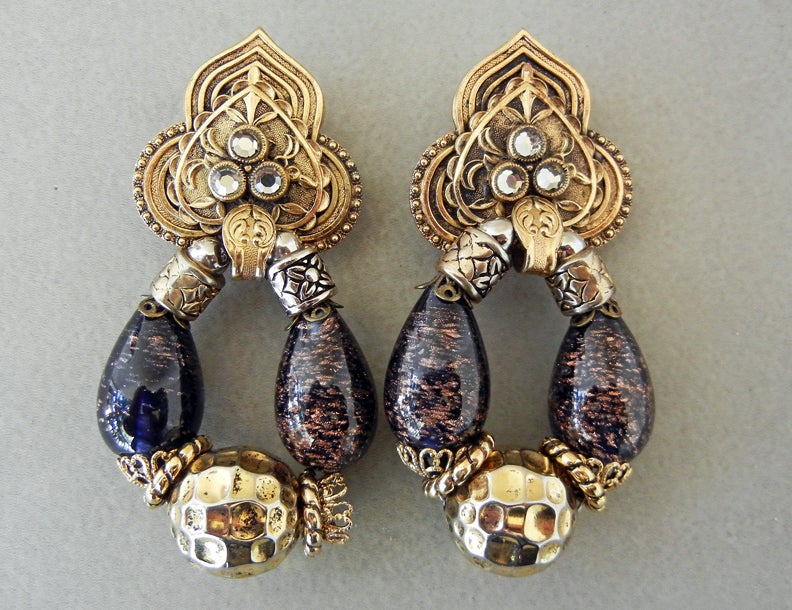 Noted Paris jewelry designer, Zoe Coste baroque style dangle earrings fashioned of antique gold metal with hanging oval shape consisting of large gold flecked glass beads, hammered large beads, and filigree small beads.  Top inset with 3 glass or