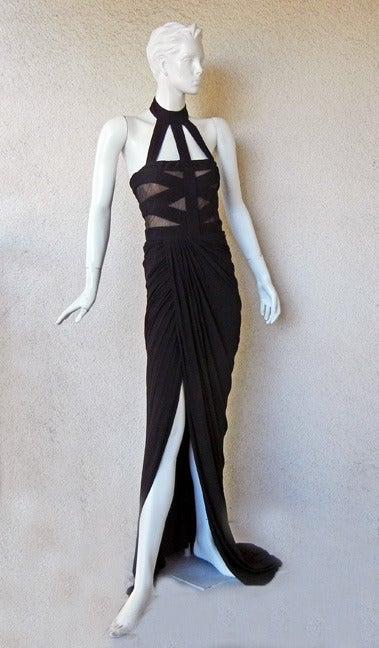 Alexander Mcqueen black jersey halter neckline bondage dress. Boasts a cut-out bodice; sheer panels and a skirt that that features a wrap effect with a front split. Thigh high tastefully designed side slit. Bodice and waist are fitted. Interior