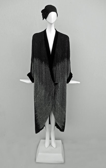 Rare Paul Poiret. Opera Coat. circa 1924.  Published.

Stunning cocoon evening coat of black georgette, hand beaded overall in lines of black beads switching to gray translucent beads with a geometric ragged edge formed at the color change. The coat