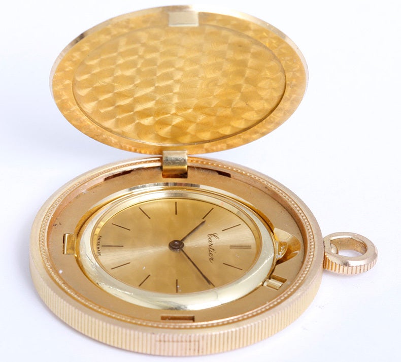 Unusual Cartier 18k yellow gold coin watch with manual-wind movement. 18k yellow gold coin case (35mm diameter) opens to reveal gold watch. Gilt dial with black baton markers. This unusual watch may be worn as a pocket watch or as a pendant.