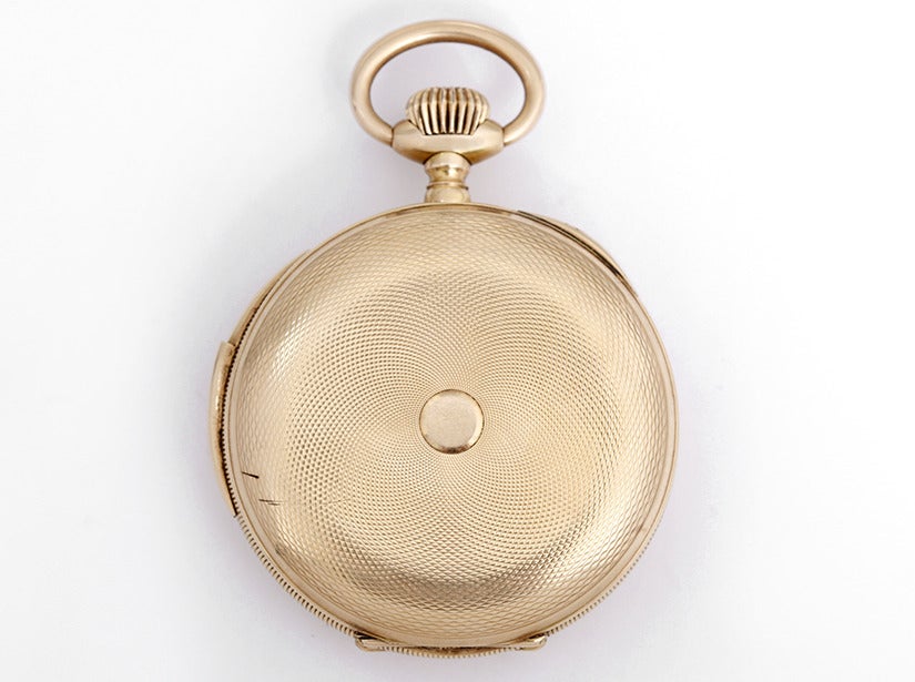 Dunand 14k yellow gold quarter repeating open face pocket watch, manual-wind movement. 51mm case with textured back and bezel. White enamel double sunk dial with black Arabic numerals, subsidiary seconds.