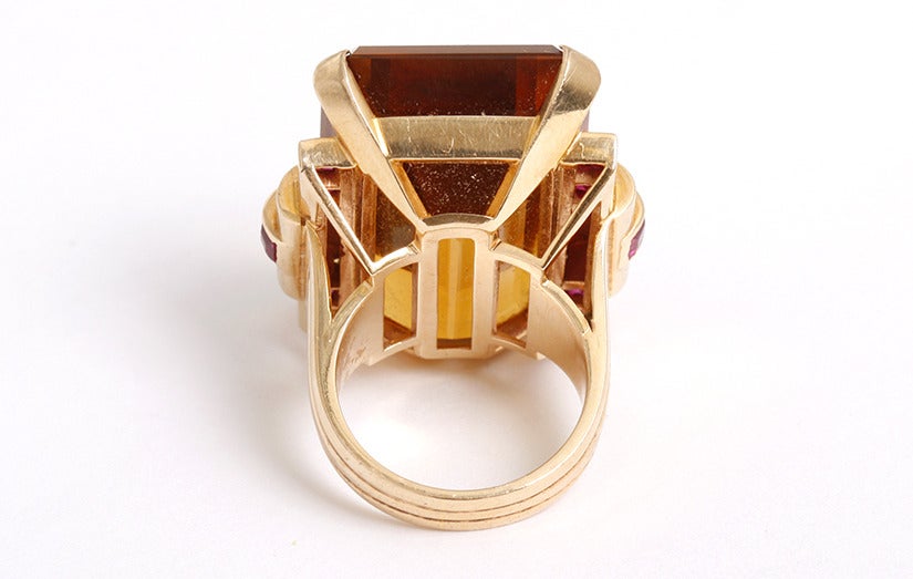 This beautiful antique ring features  apx. 50 carat emerald cut  citrine  with 7 rubies on either side. The citrine measures apx. 1 inch in length, apx. 3/4-inch in width, and apx. 1/2-inch in height. The ring is a size 6 with a total weight of 26.4